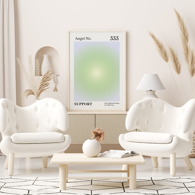 May include: A white poster with the text "Angel No. 333" and "SUPPORT" in black font. The poster has a light green and purple gradient background. The poster is hanging on a white wall in a living room setting with two white armchairs and a wooden coffee table.