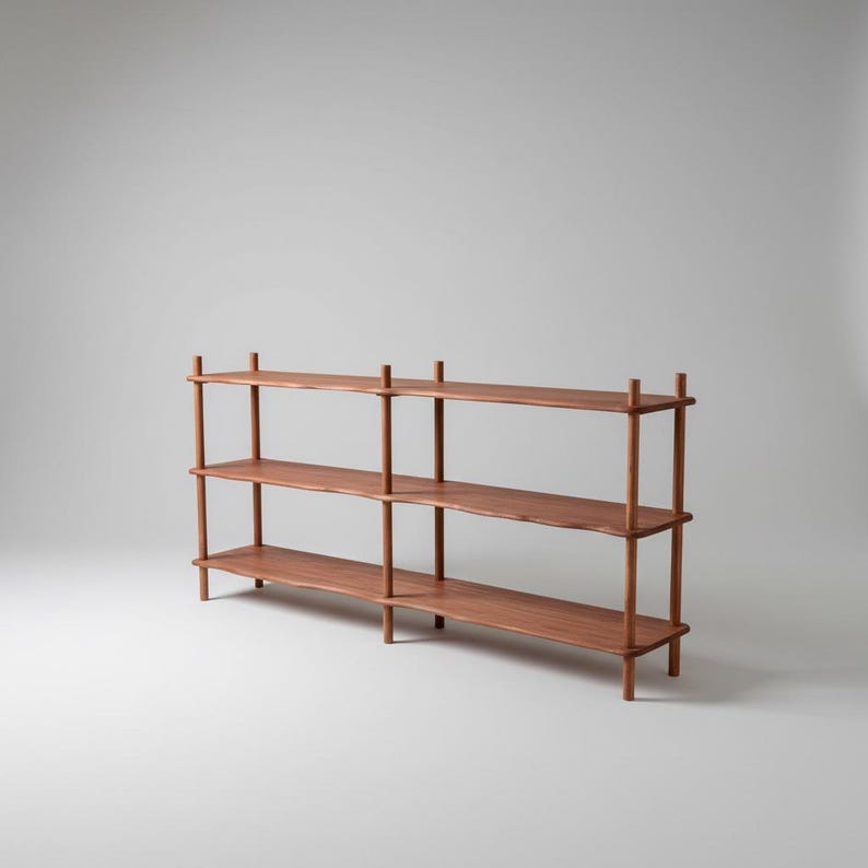 Puede incluir: Una estanter&iacute;a de madera larga de tres niveles con un acabado marr&oacute;n c&aacute;lido. La estructura consta de tres estantes horizontales sostenidos por postes cil&iacute;ndricos verticales en cada esquina y en el centro, creando un dise&ntilde;o abierto y estable.
