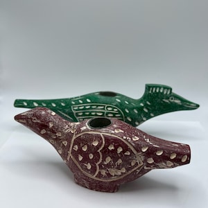 May include: Two hand-carved wooden bird candle holders. One is green with white dots and the other is maroon with white dots.