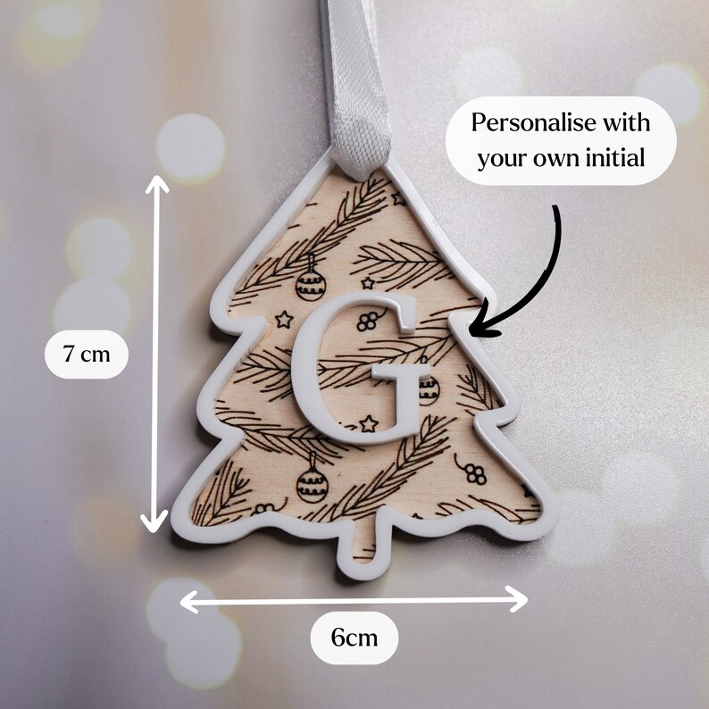 May include: White wooden Christmas tree ornament with a brown woodgrain pattern and a white letter "G" in the center. The ornament is 7 cm tall and 6 cm wide.  Personalise with your own initial.