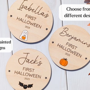 Puede incluir: Tres adornos redondos de madera con el texto "First Halloween 2023" y el nombre de un ni&ntilde;o. Los adornos presentan un fantasma, una calabaza y un murci&eacute;lago.