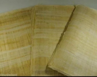 May include: A stack of handmade paper sheets with a light yellow hue. The paper has a textured surface with visible fibers and subtle variations in color, suggesting a natural, organic quality. The sheets are stacked neatly, with the edges slightly uneven.