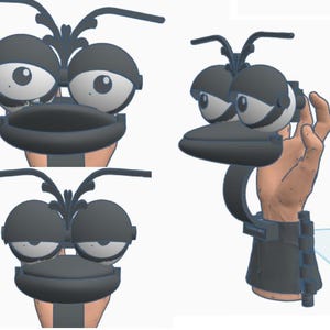 May include: A whimsical, cartoonish, black and white character head with large, expressive eyes and a beak-like structure. The design includes a wrist-worn component, suggesting a wearable accessory or prop. The overall aesthetic is playful and imaginative.