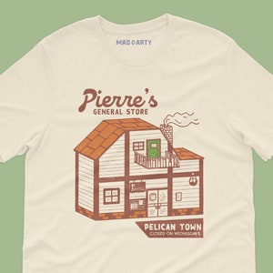 Peut inclure: Un t-shirt beige avec une illustration vintage d'un bâtiment avec le texte "Pierre's General Store" et "Pelican Town Closed on Wednesdays".