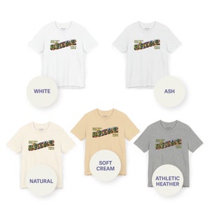 May include: Five t-shirts in different colors with the text "Greetings from Shire PUDDLE EARTH" printed on the front. The colors are white, ash, natural, soft cream, and athletic heather.