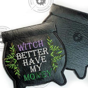May include: Two black cauldron-shaped pouches made of textured material. The front pouch features embroidered green leafy vines framing the purple and white text that reads WITCH BETTER HAVE MY MONEY. The back pouch is plain black.