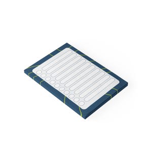 May include: A rectangular notepad with a blue cover and a white interior. The notepad features a grid of lined spaces and check boxes. The edges of the notepad are accented with a green and yellow geometric pattern.