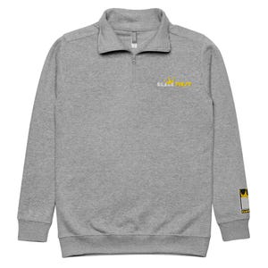 May include: A gray quarter-zip sweatshirt with a gold crown and the text "Black First" embroidered on the chest. The sweatshirt has a gold crown patch on the right sleeve.