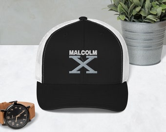 May include: Black and white trucker hat with a white mesh back. The hat has a black brim and features the text "MALCOLM X" embroidered in white on the front.