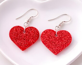 Pendientes de corazón con purpurina roja, piel sintética y ganchos de plata de ley.
