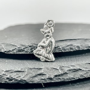 Puede incluir: Encanto de plata con una escultura detallada de un duende o gnomo sentado con un sombrero puntiagudo y una expresión traviesa.