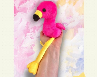May include: Pink flamingo plush toy with yellow legs and beak. The toy is 12 inches (30.5 cm) tall.