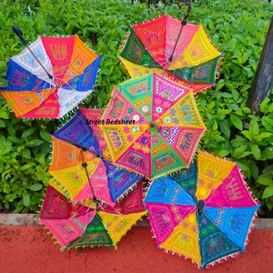 Puede incluir: Cinco paraguas coloridos con dise&ntilde;os bordados, incluyendo elefantes, flores y patrones geom&eacute;tricos. Los paraguas est&aacute;n hechos de tela y tienen mangos de madera.