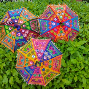 Puede incluir: Tres paraguas coloridos con bordados intrincados y trabajo de espejo. Los paraguas est&aacute;n decorados con patrones florales, formas geom&eacute;tricas y elefantes. Los paraguas son una mezcla vibrante de rojo, naranja, amarillo, verde, azul y morado.