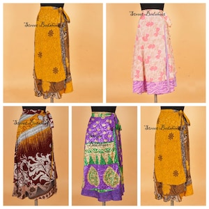 May include: Five wrap skirts displayed on mannequins, featuring various patterns and colors including yellow, pink, maroon, and purple. Each skirt has a side tie closure and a layered design with intricate floral and geometric prints throughout.
