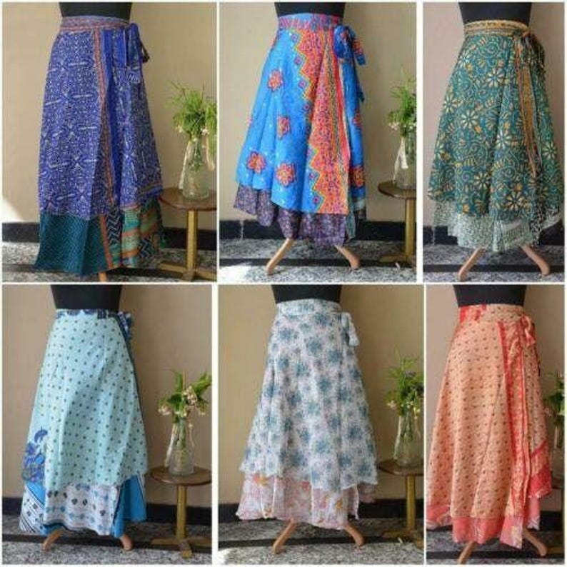May include: A collection of six wrap skirts displayed on mannequins, each featuring distinct patterns and color palettes including blue, teal, light blue, white, and peach, with layered fabric designs and tie-waist closures for each garment.