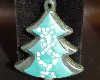 May include: A teal green Christmas tree ornament with white dots. The ornament has a loop at the top for hanging.