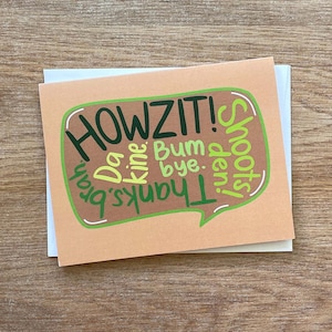 May include: A peach-colored card with a speech bubble that says "HOWZIT!" in green and brown lettering. Inside the speech bubble are the words "Thanks", "Da", "kine", "Bum", "bye", and "Smooches" in green and brown lettering.