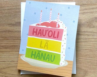 Tarjeta de felicitación de cumpleaños hawaiana, doblada, interior en blanco. Pastel Hau'oli La Hanau, azul.