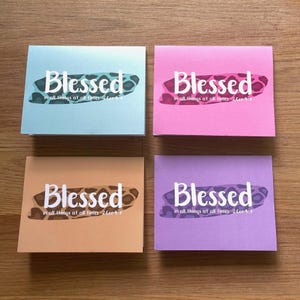 May include: Four cards with a light blue, pink, orange, and purple background. Each card has a white leopard print design with the word "Blessed" in white text and the phrase "in all things at all times. 2 Cor 9:8" in smaller white text.
