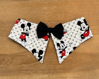 May include: A white fabric collar with a black bow tie and a Mickey Mouse print. The collar has a scalloped edge and features Mickey Mouse in various poses.