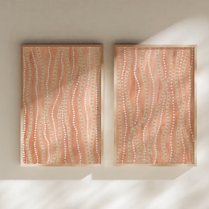 May include: Two framed abstract art prints. Each print has a peach background with vertical wavy lines of white and beige dots. The frames are light wood, adding a natural touch to the artwork.