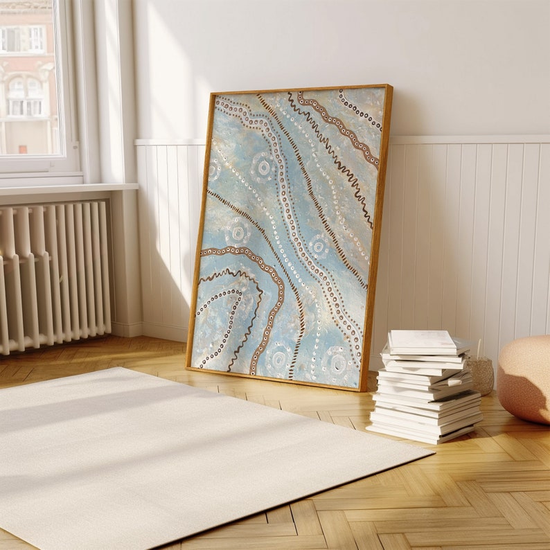 May include: A framed abstract painting with a blue background and brown and white patterns. The painting is in a wooden frame and is hanging on a white wall.