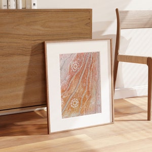 May include: A framed abstract painting with a white background and a brown, orange, and white design. The design features a series of wavy lines and circles.