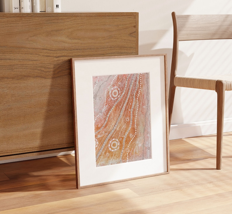 May include: A framed abstract painting with a white background and a brown, orange, and white design. The design features a series of wavy lines and circles.