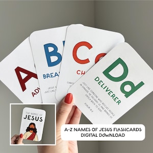 Puede incluir: Un juego de tarjetas didácticas A-Z Nombres de Jesús. Las tarjetas presentan letras grandes y coloridas y palabras correspondientes como "Advocate" y "Deliverer". La imagen incluye una tarjeta pequeña con una ilustración de Jesús y el texto "The Names of Jesus".