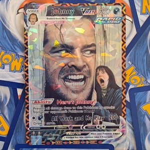 May include: A Pokemon trading card featuring a character from the movie "The Shining" with the text "Johnny VMAX 237" and "Here's Johnny!" The card is red, black, and white with a holographic finish.