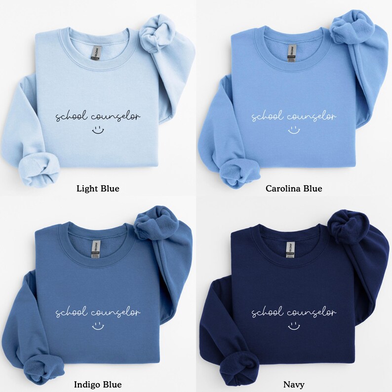 Pode incluir: Quatro moletons com gola redonda em diferentes tons de azul, cada um com o texto "school counselor" e um rosto sorridente bordado em branco.