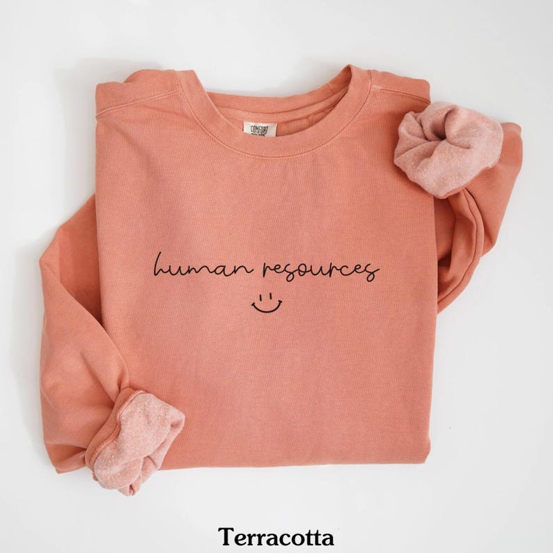 May include: Terracotta colored sweatshirt with the text "human resources" and a smiley face in black.