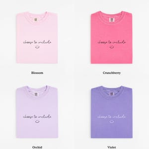 May include: Four folded t-shirts in different colors: blossom, crunchberry, orchid, and violet. Each shirt has the phrase "choose to include" and a smiling face printed on the front.