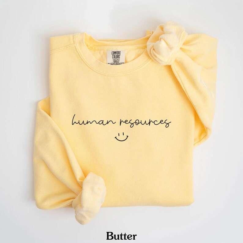 May include: A yellow sweatshirt with the text "human resources" and a smiley face in black.