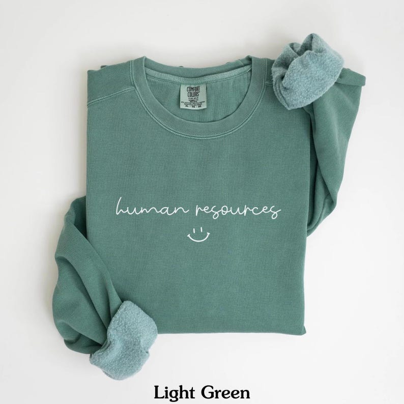 May include: Light green sweatshirt with the text "human resources" and a smiley face in white.