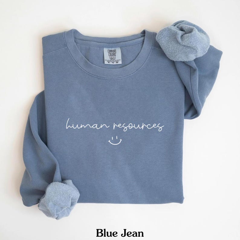 May include: A blue sweatshirt with the text "human resources" and a smiley face in white.