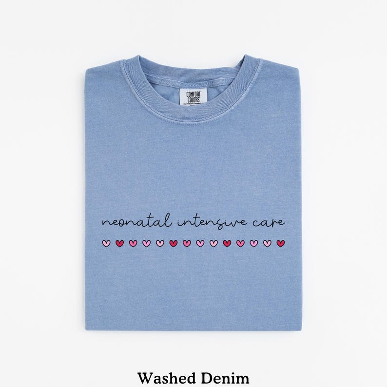 May include: A light blue t-shirt with the text "neonatal intensive care" and a row of pink and red hearts. The shirt is made of a washed denim fabric.