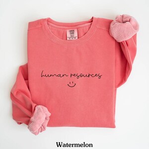 May include: Watermelon colored sweatshirt with the text "human resources" and a smiley face.