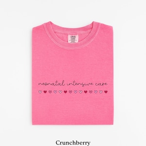 May include: Pink t-shirt with the text "neonatal intensive care" and a row of small hearts in different shades of pink and red.