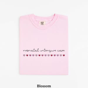 May include: Pink t-shirt with the text "neonatal intensive care" and a row of pink and red hearts.