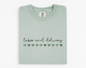 May include: A light green t-shirt with the text "labor and delivery" in black script. A row of green hearts are below the text.