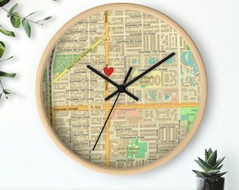 May include: A round wooden clock with a map of Dania Beach, Florida. The clock face features a red heart in the center and the hands are set to 12:00. The map includes street names, landmarks, and a school.