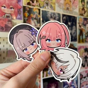 May include: Three anime-style character stickers with blush on their cheeks. The stickers are on a white background and feature pink, purple, and white hair.