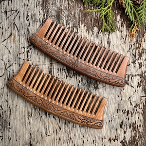 May include: Two wooden combs with intricate carved designs. The combs are brown and have a curved shape.