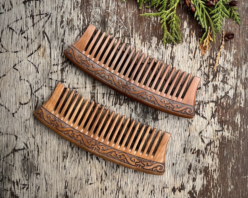 May include: Two wooden combs with intricate carved designs. The combs are brown and have a curved shape.