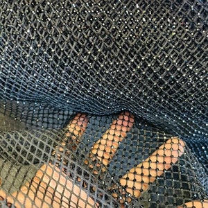 May include: Black mesh fabric with small, sparkly silver beads. The fabric has a diamond-shaped pattern.