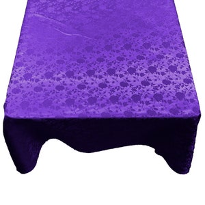 Peut inclure: Une nappe de table violette avec un motif floral. La nappe a un effet dégradé, avec un violet plus foncé en bas et un violet plus clair en haut.