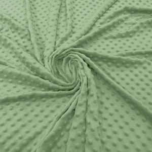 May include: A soft, green fabric with a textured, dotted pattern. The fabric is folded and draped, showing the texture and color.