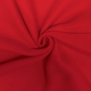 Puede incluir: Primer plano de una tela polar roja vibrante. La tela es suave y tiene un ligero brillo, con pliegues y un patrón en espiral en el centro. El material es liso y parece ser de color sólido.